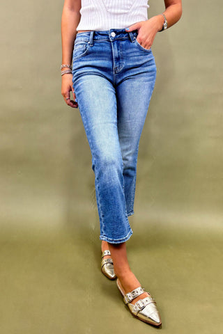 Person wearing blue jeans and silver shoes on a plain background