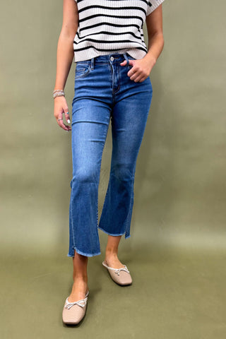 Person wearing blue jeans and a striped shirt on a green background