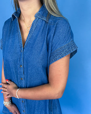 Woman wearing a blue denim dress against a blue background