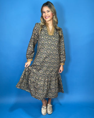 Black floral midi dress with long sleeves, tiered skirt, and contrasting camel ruffle neckline and cuffs.