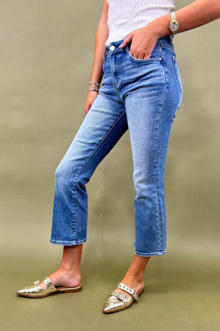 Person wearing blue jeans and gold flats on a green background