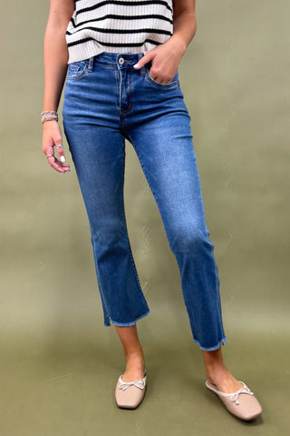 Person wearing blue jeans and a striped top on a green background