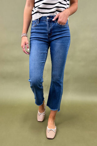 Person wearing blue jeans and a striped shirt on a green background