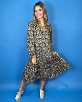 Black floral midi dress with long sleeves, tiered skirt, and contrasting camel ruffle neckline and cuffs.