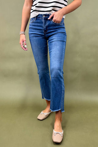 Person wearing blue jeans and a striped shirt on a green background