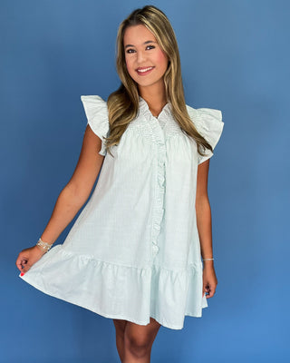 Woman wearing a white dress with ruffled sleeves against a blue background