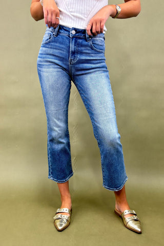 Person wearing blue jeans and gold flats on a green background