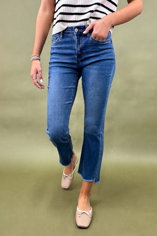 Person wearing blue jeans and a striped shirt on a green background