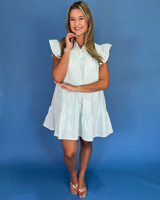 Woman wearing a white dress with ruffled sleeves against a blue background