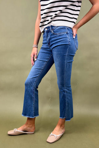 Person wearing blue jeans and a striped top on a green background