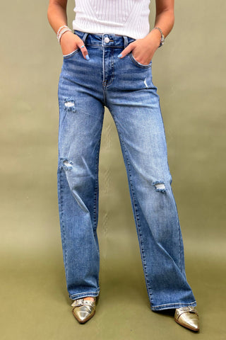 Person wearing blue jeans with a plain background