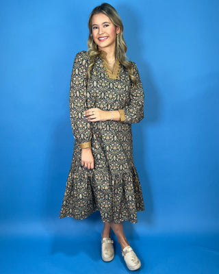 Black floral midi dress with long sleeves, tiered skirt, and contrasting camel ruffle neckline and cuffs.