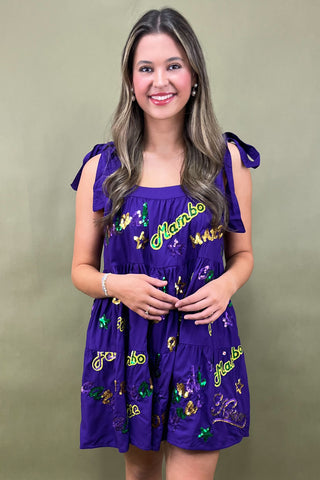 Woman wearing a purple dress with colorful designs on a green background