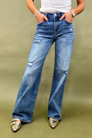 Person wearing blue jeans with a plain background