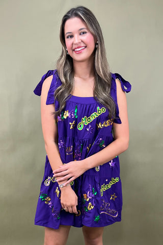 Woman wearing a purple dress with colorful designs and text on a green background