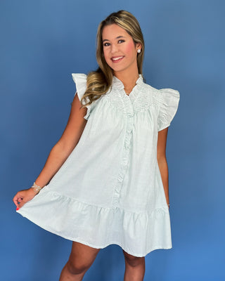Woman wearing a white dress with ruffled sleeves against a blue background