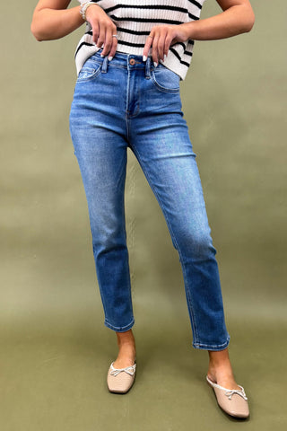 Person wearing blue jeans and a striped shirt on a green background