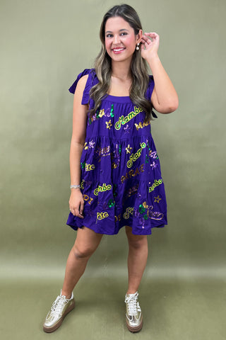 Woman wearing a purple dress with colorful patterns on a green background