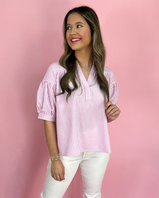 Woman wearing a pink and white striped blouse against a pink background