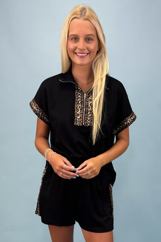 Woman wearing a black outfit with leopard print accents against a light blue background