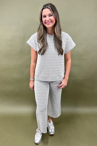 Woman wearing a matching patterned top and pants set against a plain background