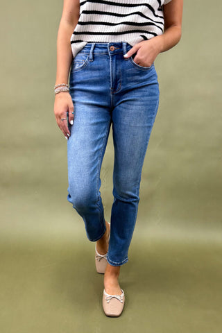Person wearing blue jeans and a striped top on a green background