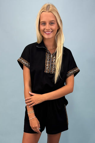 Woman wearing a black outfit with leopard print details on a blue background