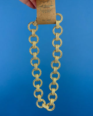 Shop the Gold Link Necklace featuring oversized textured gold links and a stylish toggle clasp for a timeless statement accessory.