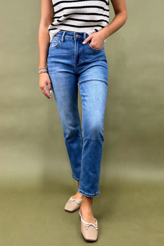 Person wearing blue jeans and a striped top on a green background
