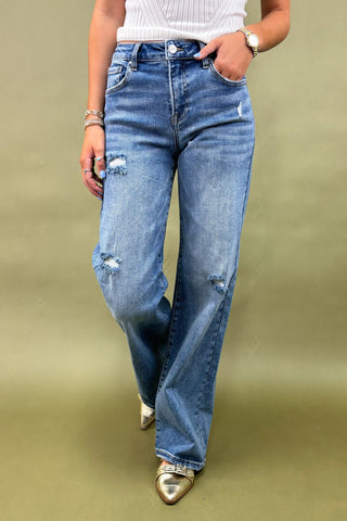Person wearing blue jeans with a plain background