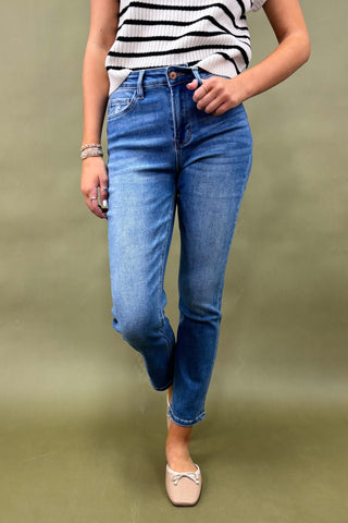Person wearing blue jeans and a striped shirt on a green background