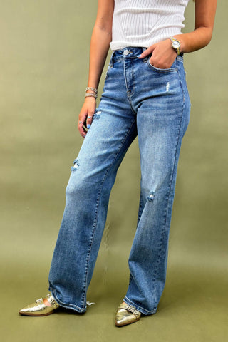 Person wearing blue jeans with a plain background