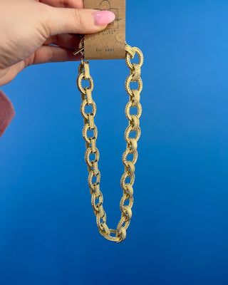 Shop the Gold Link Necklace featuring oversized textured gold links and a stylish toggle clasp for a timeless statement accessory.