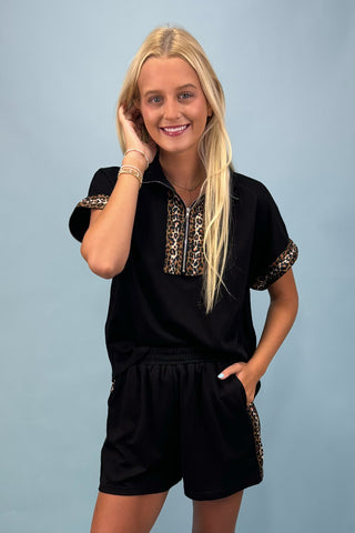 Woman wearing a black outfit with gold accents against a light blue background