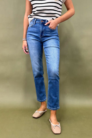 Person wearing blue jeans and a striped shirt on a green background