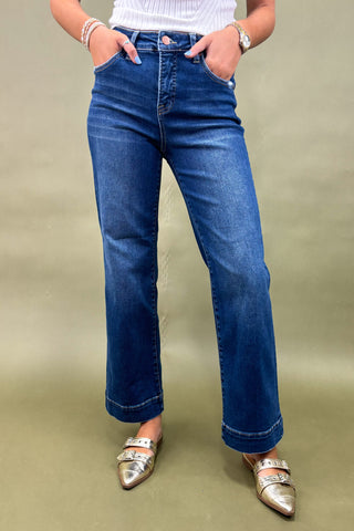 Person wearing blue jeans and silver shoes on a beige background