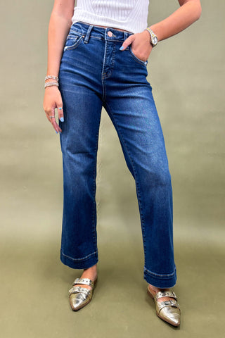 Person wearing blue jeans and silver shoes on a beige background