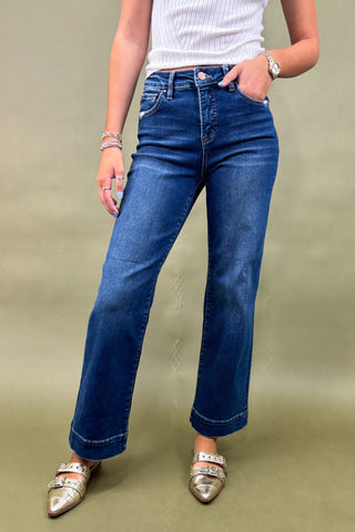 Person wearing blue jeans and silver shoes on a green background