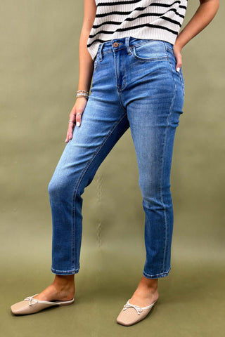 Person wearing blue jeans and a striped top on a green background
