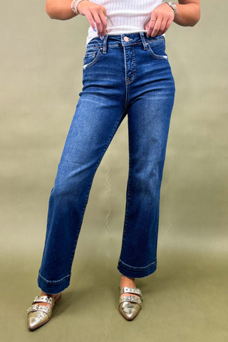 Person wearing blue jeans and silver shoes on a beige background