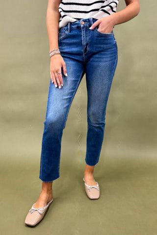 Person wearing blue jeans and a striped shirt on a green background