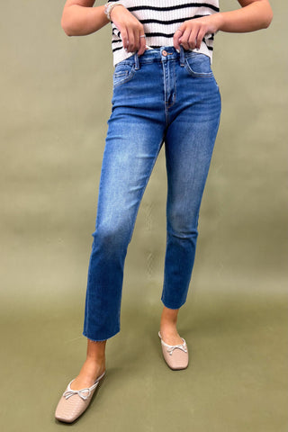 Person wearing blue jeans and a striped shirt on a green background