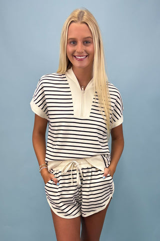 Woman wearing a black and white striped outfit against a blue background