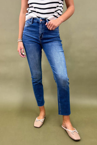 Person wearing blue jeans and a striped shirt on a green background