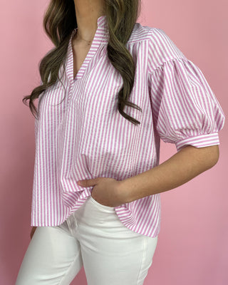 Woman wearing a pink and white striped blouse against a pink background