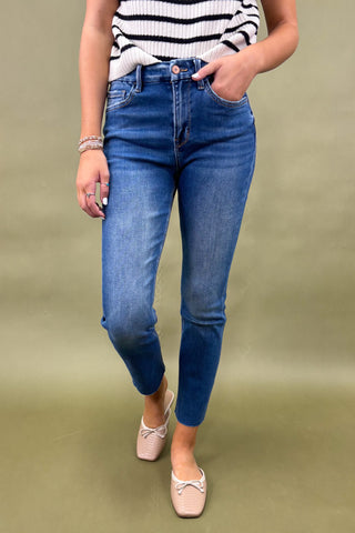 Person wearing blue jeans and a striped top on a green background