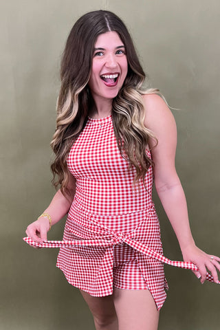 Woman wearing a red and white checkered outfit against a green background