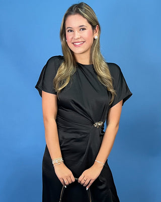 a black midi dress with short flutter sleeves, a draped satin-like finish, and a matching tie belt at the waist.