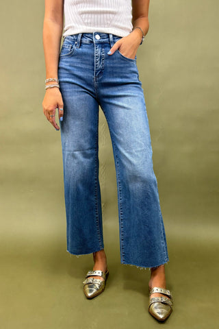 Person wearing blue jeans and a white top on a green background