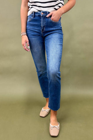 Person wearing blue jeans and a striped shirt on a green background